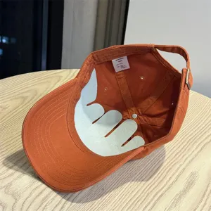 Detail view of a solid orange cotton baseball cap showing interior structure and brand label.