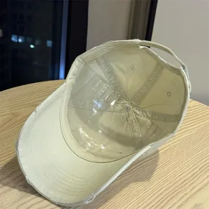 Detailed view of the distressed beige baseball cap with wide brim and internal plastic support.