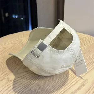 Detailed shot of beige washed vintage baseball cap with metal buckle and hanging tag.