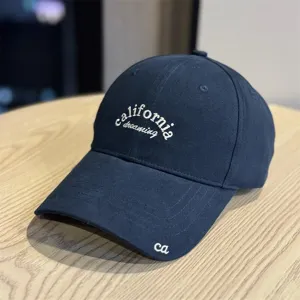 Detailed view of dark blue retro baseball cap with California dreaming embroidery on the front.