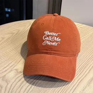 Detailaufnahme der orangefarbenen Baumwoll-Baseballkappe mit weißer Bestickung und Text.