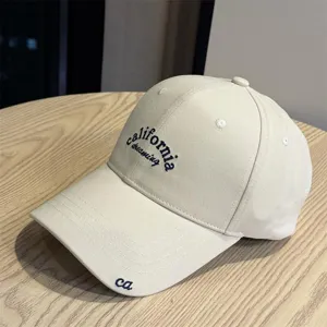 Detail view of a beige vintage baseball cap with California dreaming embroidery and curved brim.