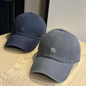 Detail view of Japanese minimalist embroidered baseball caps in navy and dark grey colors.