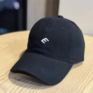 Vista detallada de gorra de béisbol negra de algodón con logotipo E bordado en blanco.
