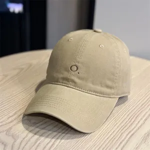 Close-up view of a khaki baseball cap featuring a delicate embroidered letter O detail.