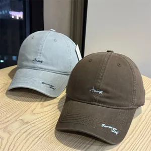 Detail shot of Japanese style letter embroidered baseball caps in grey and brown colors.