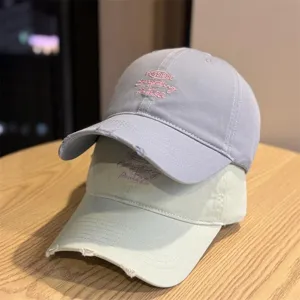 Detail view of distressed soft top baseball caps featuring neat embroidery text and stacking display.