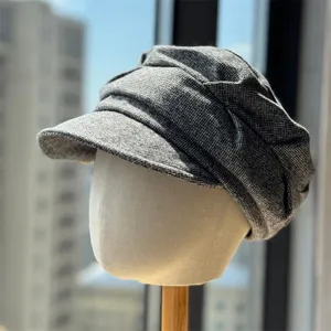 Close-up detail of grey tweed newsboy cap, vintage octagonal woolen hat display on mannequin.