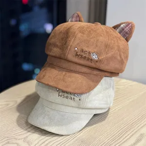 Close-up detail of cute cat ear beret hat with soft suede texture and embroidered lettering.