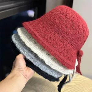 Primo piano dettagliato di comodi cappelli da pescatore in maglia in vari colori con fiocco.