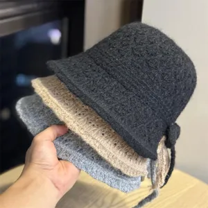 Dettaglio cappello secchiello in maglia con trama morbida e fiocco laterale colorato.