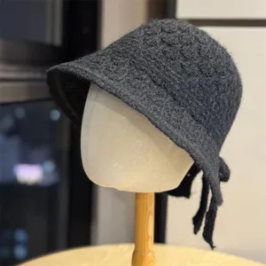 Vista dettagliata del cappello bucket in maglia grigia scura con fiocco, morbida lana calda.