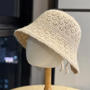 Vista dettagliata del morbido cappello a secchiello in maglia con delicato motivo e grazioso fiocco.