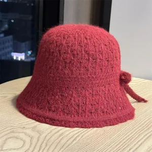 Primo piano dettagliato del cappello da pescatore in maglia rossa con fiocco laterale e lana.