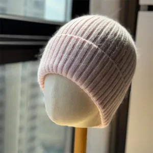 Primo piano dettagliato della morbida trama in maglia rosa del caldo berretto invernale.