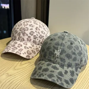 Primo piano di cappellini da baseball leopardati di tendenza con lettere ricamate.