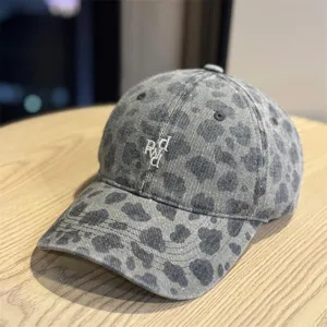 Primo piano del cappellino leopardato grigio con delicato ricamo bianco sulla corona morbida.
