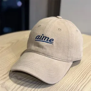 Close-up view of khaki baseball cap featuring blue embroidered lettering and wide brim design.