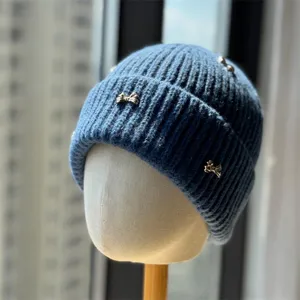 Close-up detail of women's blue winter knitted beanie hat featuring elegant metal bow decors.