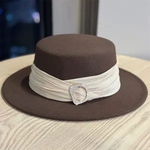 Detail shot of retro wool flat-top hat with cream ribbon and crystal buckle, elegant style.