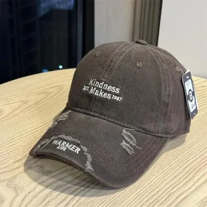 Close-up view of the distressed brown baseball cap featuring white embroidery and worn details.