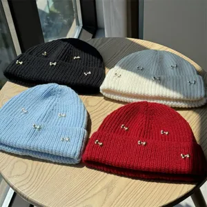 Detailed view of women's autumn winter knit beanies with cute silver bow decorations and cozy fabric.