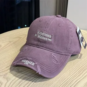 Detail view of the vintage purple washed baseball cap featuring front embroidery and ripped brim.