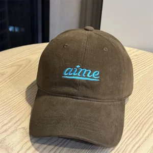 Brown corduroy baseball cap with blue embroidered letter design, soft top and wide brim style.