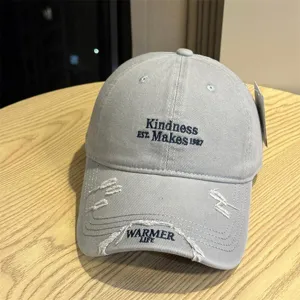 Detailed view of grey distressed baseball cap with stylish embroidery and washed cotton fabric.
