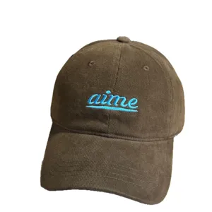 Brown corduroy baseball hat with blue embroidered aime script text, wide brim soft top cap.