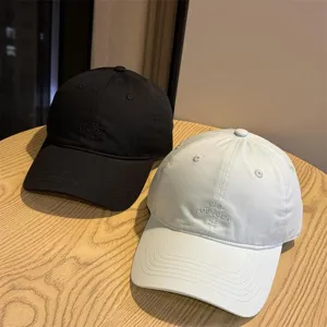 Vista detallada de gorras de béisbol informales para parejas en negro y blanco bordadas.