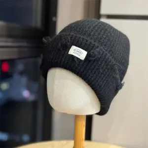 Dark grey knit beanie detail showing ribbed texture, distressed edges and woven label.