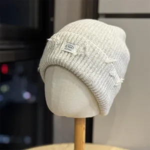 Close-up of the textured knit detail and frayed patch on the warm slouchy beanie hat.