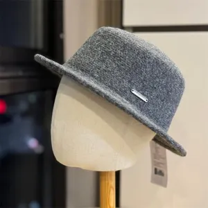 Close-up detail of the elegant grey wool fedora hat with metallic brand badge and tag.