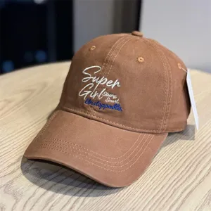 Detail view of brown embroidered baseball cap showing front letter stitching and soft crown design.