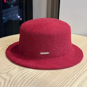 Close-up detail of the elegant red wool bucket hat featuring a chic metal logo plate.