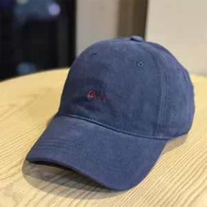 Close-up detail of dark blue washed cotton dad hat with red embroidered text design