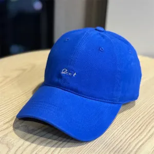 Close-up of royal blue baseball cap with white embroidered text detail and soft top.