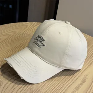 Detailed view of casual beige baseball cap with distressed brim and custom front embroidery.