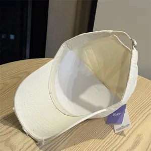 Detailed view of the baseball cap interior and branded hangtag, showing fine stitching and cotton fabric.