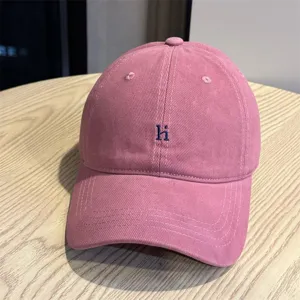 Pink washed cotton baseball cap with blue embroidered letter, breathable soft hat for daily wear.