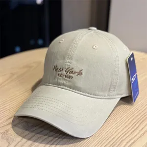 Close-up of beige baseball cap with New York embroidery, showcasing fine stitching and brim.