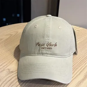 Close-up of beige cotton baseball cap featuring front New York embroidered lettering and wide brim.