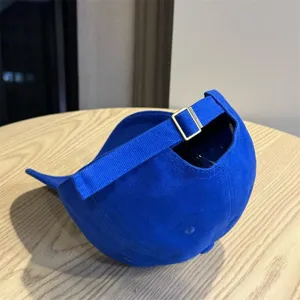 Blue cotton baseball cap detail showing the back view with an adjustable metal buckle strap.