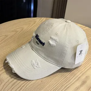 Berretto da baseball beige slavato con lettere ricamate e particolari dettagli strappati.
