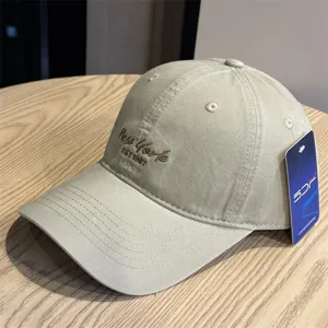 Beige baseball cap detail view showing embroidered New York text and side product tag.