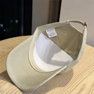 Close up view of the beige baseball cap interior showing the washing label and curved brim.