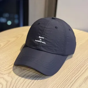 Vista detallada de la gorra de béisbol deportiva ligera y de secado rápido con texto impreso.