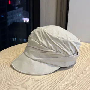 Close-up detail of the beige ruched newsboy hat, showing unique draped texture and fine fabric.