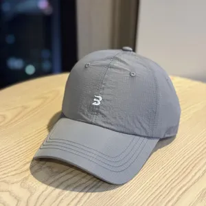 Detail shot of a minimalist grey quick-dry waterproof baseball cap with white embroidery.